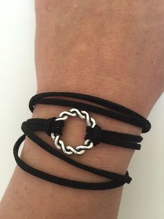 a close up of a person's arm wearing a black bracelet with a silver circle on it