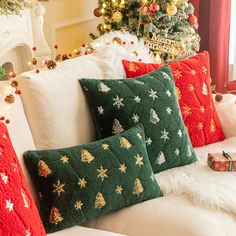 christmas pillows on a couch in front of a tree