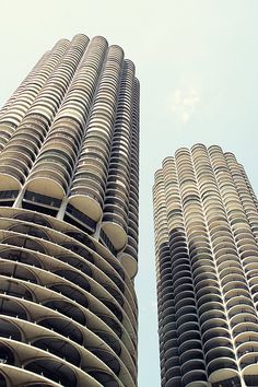 two tall buildings with balconies on the top and bottom, against a blue sky