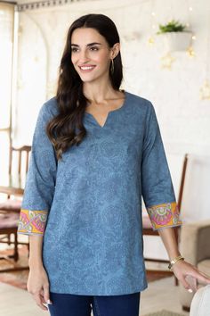 A lovely paisley pattern swirls across this cadet blue tunic designed by India's Isha Jain. Crafted from 100% cotton, the tunic features a screen-printed paisley motif and a block-printed floral pattern on contrasting marigold cuffs. Lateral slits let you slip the tunic over your head without fumbling with buttons or zippers. Blue Cotton Tops With Paisley Print, Blue Cotton V-neck Tunic, Blue Long Sleeve Tops With Printed Motifs, Printed Cotton Tops With Split Neck, Cotton Printed Top With Split Neck, Cotton Printed Split Neck Tops, Cotton Split Neck Printed Tops, Blue Bohemian Tops With Printed Motifs, Blue Block Print Straight Kurta Top