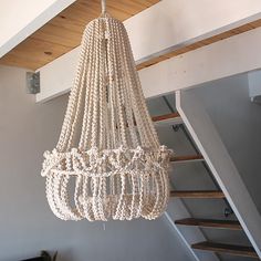 a white chandelier hanging from the ceiling in a room with stairs and wood paneling