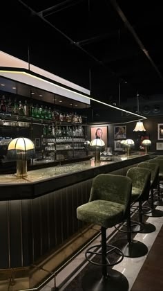 a dimly lit bar with stools and lamps on the sidelines in front of it