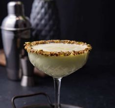 a close up of a drink in a glass on a table with a shaker