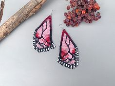 pink and black beaded butterfly earrings next to dried flowers