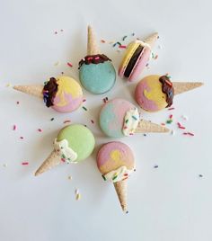 five ice cream cones with different colored frosting and sprinkles on them