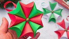 someone is holding an origami umbrella in front of other ornaments on the table