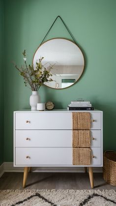 a white dresser topped with a mirror next to a plant