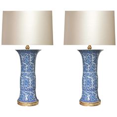 two blue and white vases with lamps on top of each one, side by side