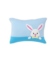 a blue knitted pillow with a white bunny on it