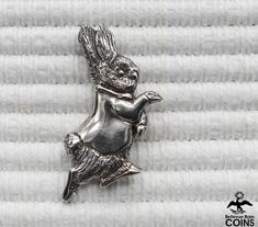 a silver pin with an image of a bird on it's back, sitting on top of a white towel