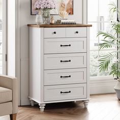 a white chest of drawers in a living room with flowers on the top and bottom