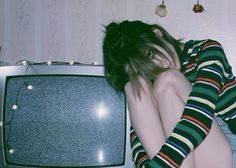 a woman laying on top of a tv next to a wall