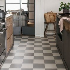 a kitchen with black and white checkered flooring, stainless steel appliances and cabinets