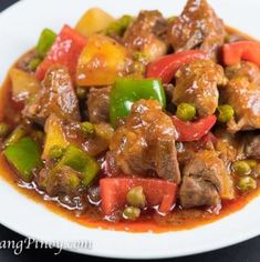 a white plate topped with meat and veggies covered in gravy on top of a table