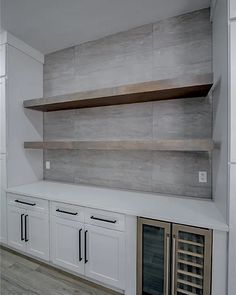 an empty kitchen with white cabinets and wine racks on the wall behind it is a built - in wine cooler