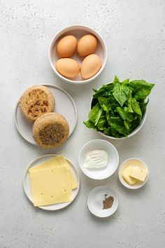 eggs, cheese, spinach and other ingredients are arranged in bowls on a table