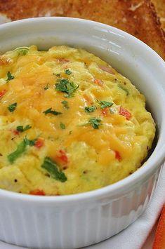 an omelet in a white dish on a plate next to bread and carrots