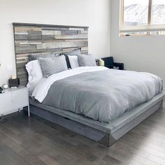 a large bed sitting in a bedroom on top of a hard wood floor next to a window