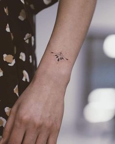 a woman's arm with a small flower tattoo on her left wrist and the other hand