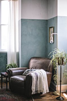 a living room with blue walls and leather chair