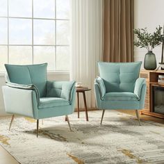 two blue chairs sitting in front of a window next to a table with a vase on it