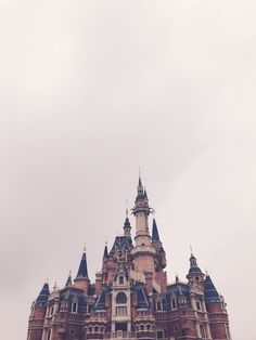 an old castle with turrets and spires is shown in the foggy day sky