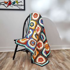 a crocheted blanket sitting on top of a chair in front of a wall