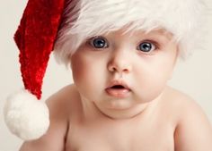 a baby wearing a santa hat looking at the camera