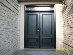 two black double doors in front of a brick building