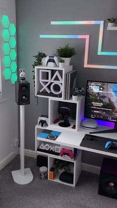 a computer desk with speakers and a monitor on it in front of a gray wall