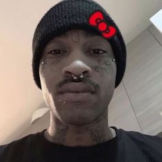 a man with piercings on his nose wearing a black shirt and a beanie