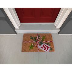 a door mat with the word joy on it and candy canes tied to it