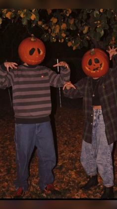 two young boys wearing pumpkin heads in the yard at night with their hands out to each other