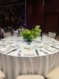 a round table with white linens and silverware is set up for a formal function