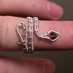 a person is holding a ring made out of metal tubes and wire with a heart on it