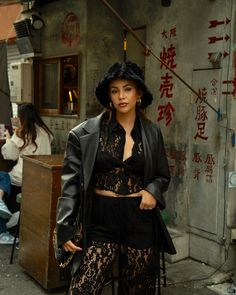 a woman standing in front of a building wearing black clothing and holding a handbag