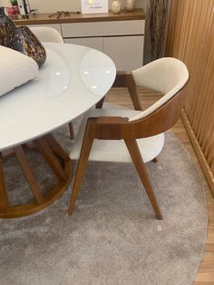 a white table with two chairs next to it on a carpeted floor in a living room