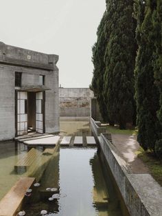 an old building with water in front of it and trees on the other side of the building