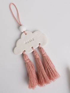 two tassels are hanging from a white cloud shaped ornament with the word,