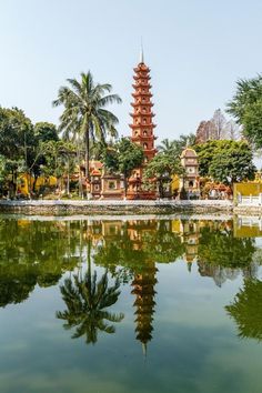 a tall tower sitting next to a lake with trees in the background on a sunny day