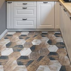 a kitchen with white cabinets and wood flooring on the counter top, along with an oven