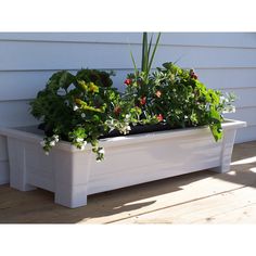 a white planter filled with lots of green plants