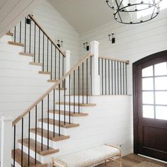 the stairs are made of wood and have white painted walls, along with black iron railings