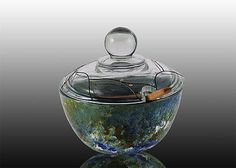 an artistic glass bowl with a lid and handle