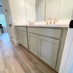 an empty bathroom with two sinks and large mirrors on the wall, along with hardwood flooring