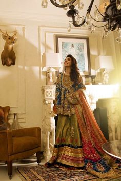 a woman standing in front of a chandelier wearing an elaborate dress and jewelry