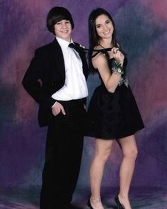 two young people posing for a photo in formal wear and tuxedo, with purple background