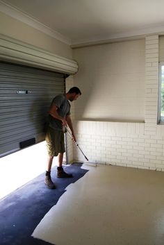 a man with a mop is cleaning the floor in an empty garage, while another man looks on