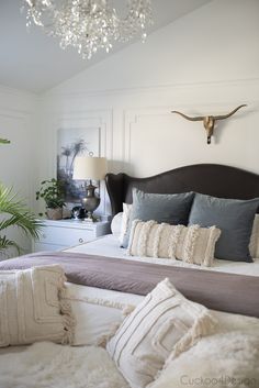 a bedroom with a bed, chandelier and pillows