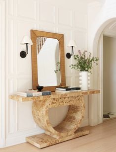 a wooden table topped with a mirror next to a vase filled with flowers